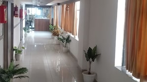 Un pasillo de hotel con una recepción, plantas en macetas y suelo de baldosas.