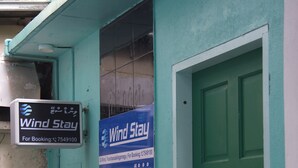 A building with a green door and a sign for Wind Stay. - Wind Stay (Malé)