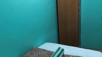 Una habitación pequeña con paredes verde azulado, un armario de madera y una cama con ropa de cama de estampado de leopardo.