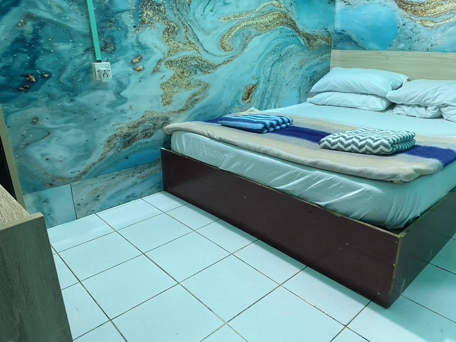 A bedroom with a bed, pillows, and a marble wall.