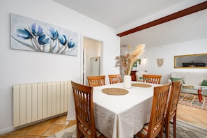 A dining area with a table set for six, surrounded by wooden chairs, a white tablecloth, and a vase with dried plants. - Family Apartment Monsa in Porec area, Istria (Mušalež)