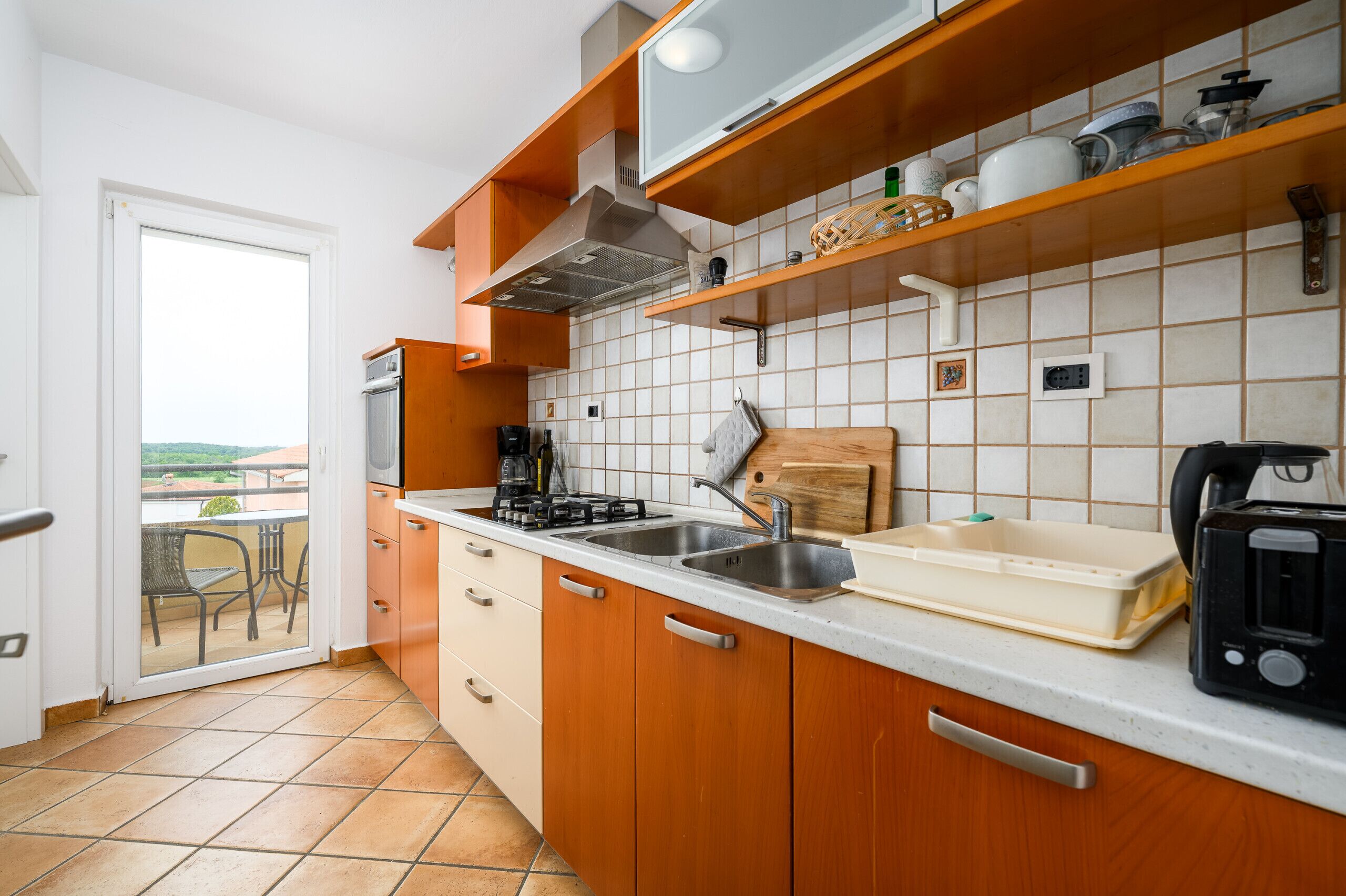 Eine Küche mit Gasherd, Spüle und Toaster. Ein Fenster bietet Blick ins Freie.