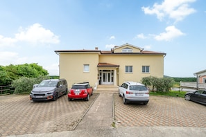 A two-story house with a tiled roof, a front entrance, and three parked cars. - Family Apartment Monsa in Porec area, Istria (Mušalež)
