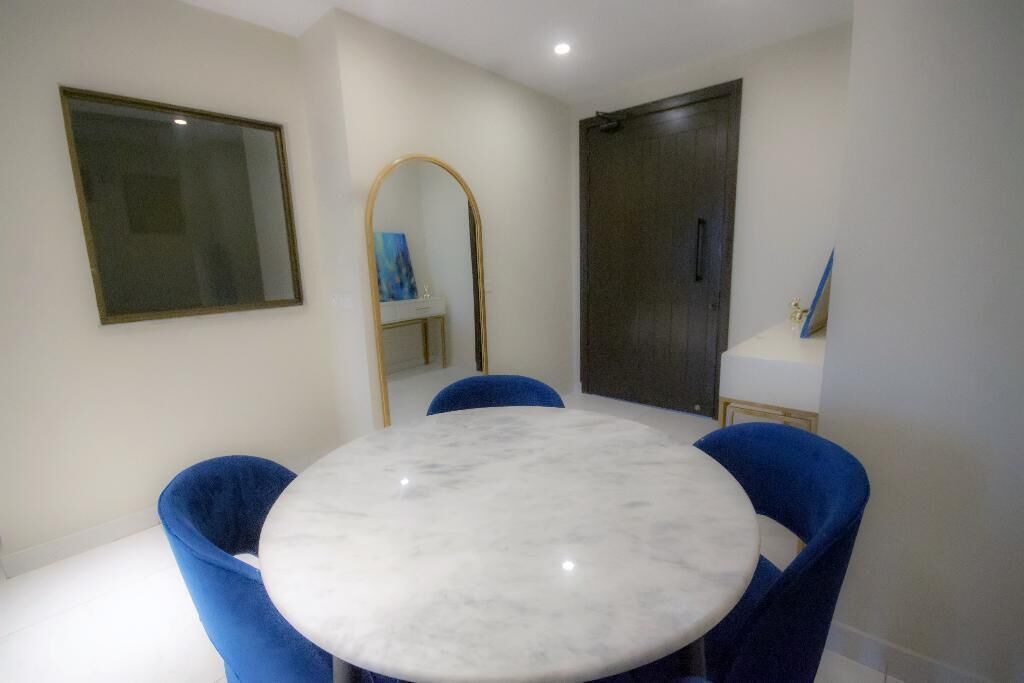 A dining area with a round marble table and blue upholstered chairs.