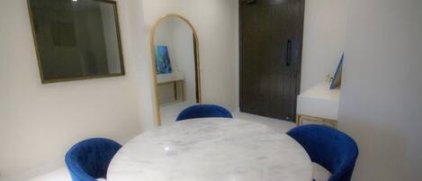 A dining area with a round marble table and blue upholstered chairs.