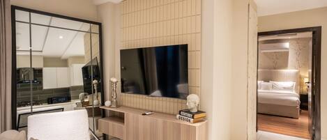 Una sala de estar moderna con un televisor de pantalla plana grande, una consola de madera y un sillón blanco.