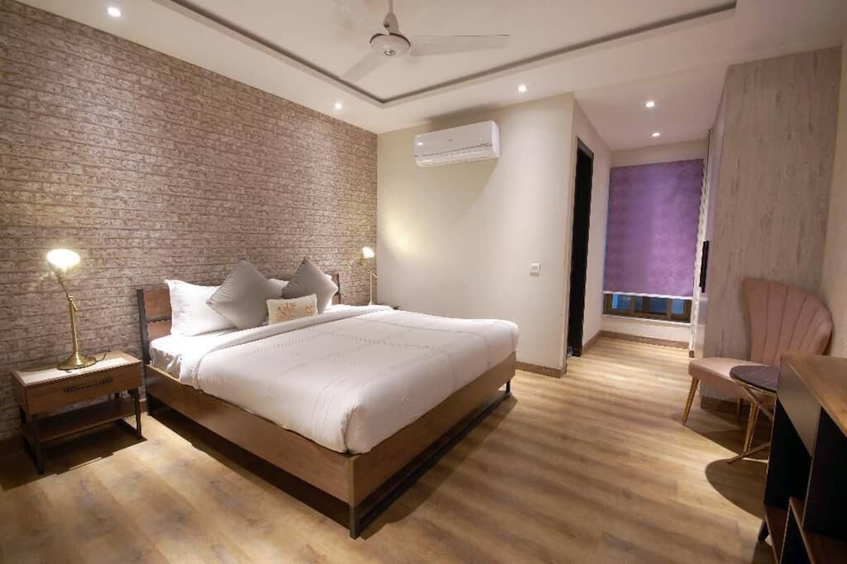 Une chambre moderne avec un lit en bois, un mur décoratif en briques et un ventilateur de plafond.