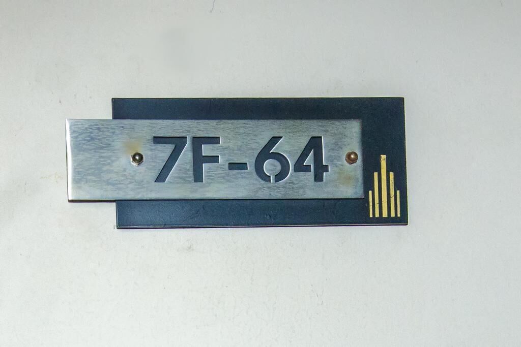 A metal plaque with the inscription "7F-64" mounted on a wall.