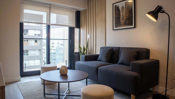 Un salon moderne avec un canapé gris, une table basse ronde et un lampadaire.