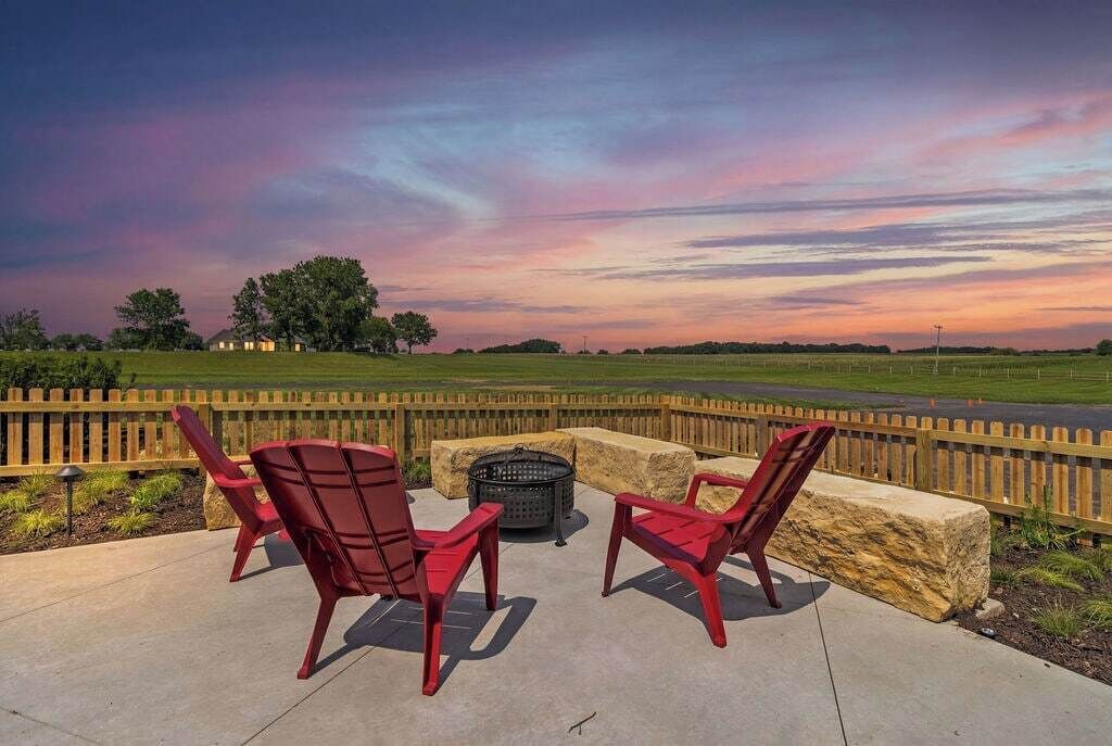 An outdoor seating area with red chairs and a fire pit.