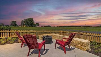 An outdoor seating area with red chairs and a fire pit.