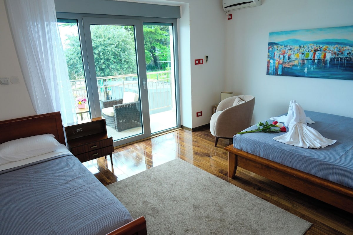A hotel room with a bed, a chair, a desk, and a painting on the wall.
