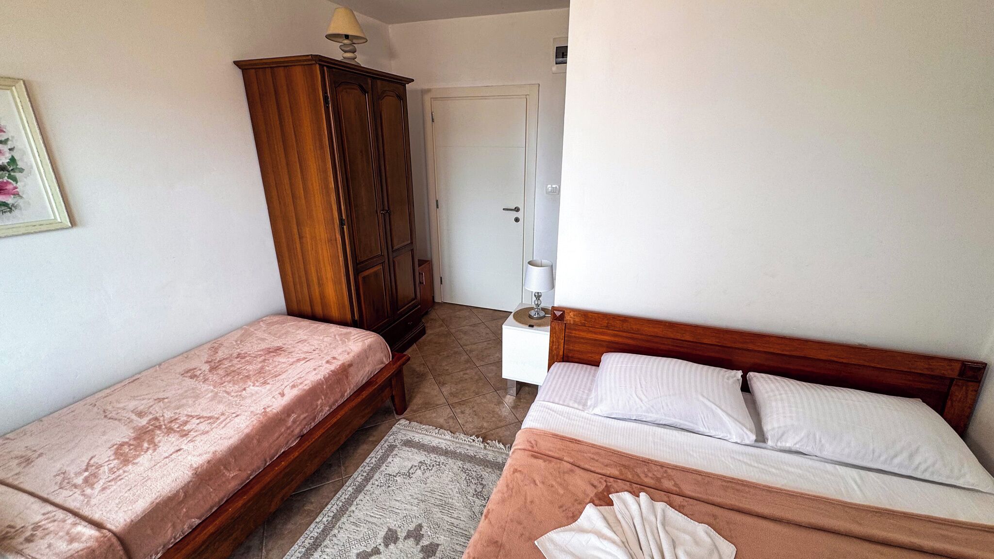 Ein Schlafzimmer mit zwei Betten, einem Kleiderschrank, einem Nachttisch und einer Tür.