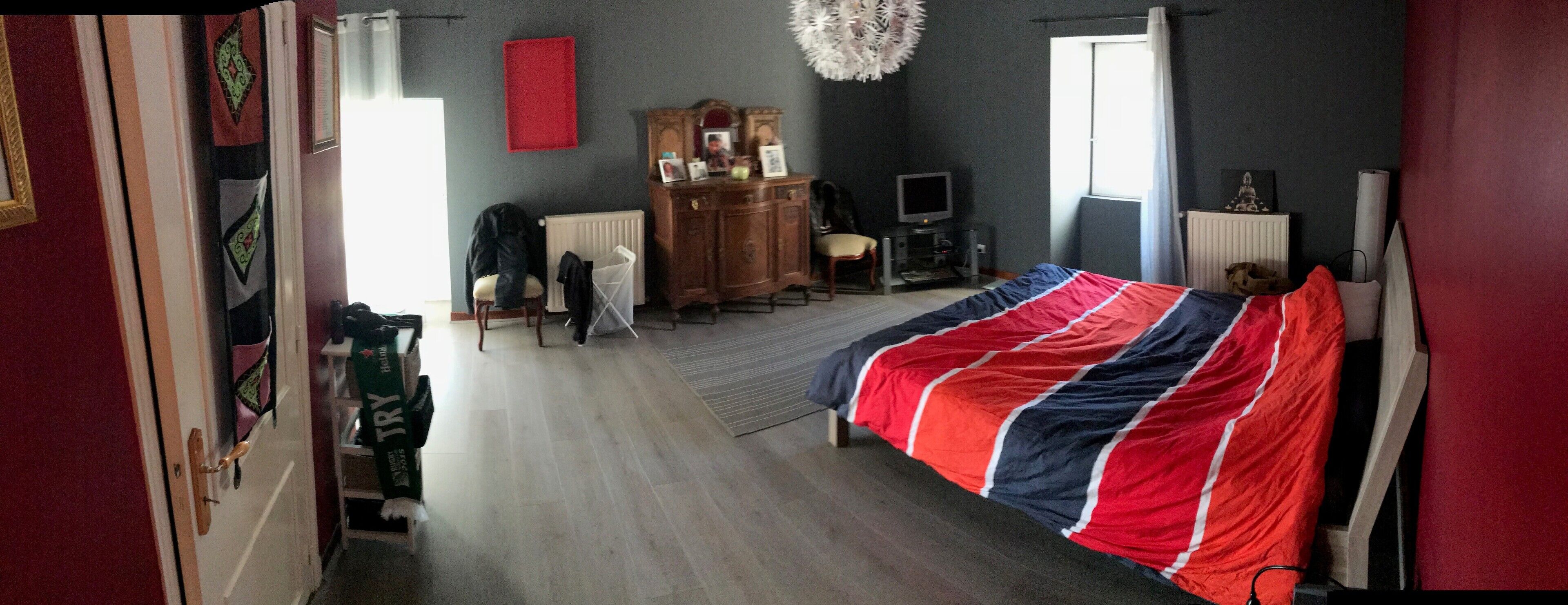 A bedroom with a bed, dresser, TV, and a window.