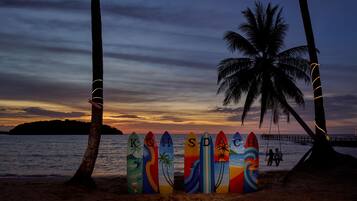 Uma praia com pranchas de surf alinhadas e palmeiras.