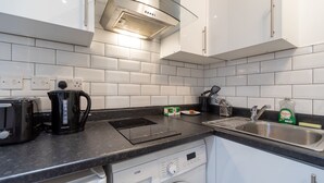 A modern kitchen with a built-in dishwasher, a coffee maker, and a sink.