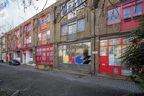 A row of red-framed buildings with large windows and a car parked in front. - Chic Shoreditch Studio,Fast Wi-Fi & Top Location (London)