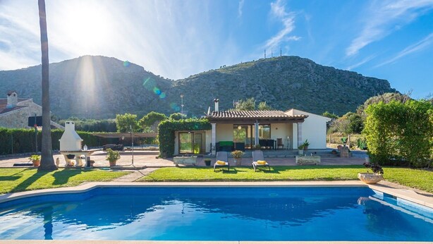 A pool with a house in the background, surrounded by greenery and a mountain. - Villa Pancho - Large garden (Alcúdia)