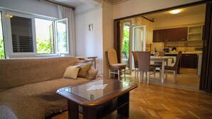 Un salon comprenant un canapé, une table basse avec un plateau en verre et un coin repas avec une table et des chaises.
