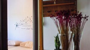 Une chambre à coucher avec un lit, un élément décoratif mural et un vase de fleurs.