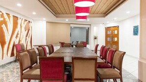 Een vergaderzaal met een lange tafel, meerdere stoelen en een rode hanglamp.