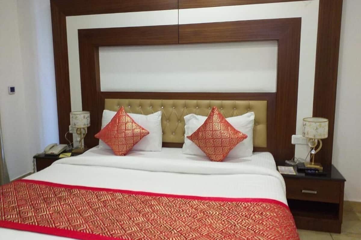A neatly made bed with a patterned bedspread, two decorative pillows, and a headboard with a light panel.