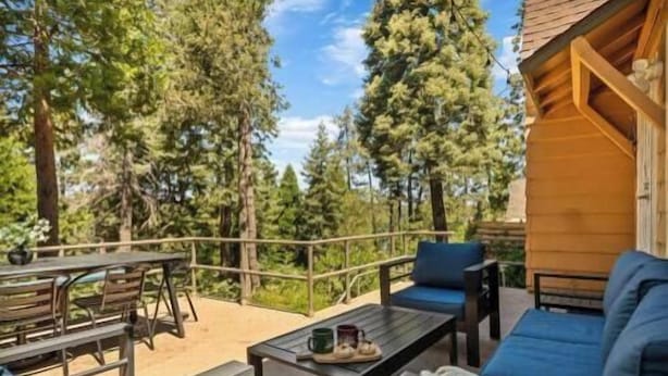 A wooden cabin with a patio area featuring a table, chairs, and a sofa.