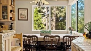 A dining area with a table and chairs, a ceiling fan, and a window with a view of trees.