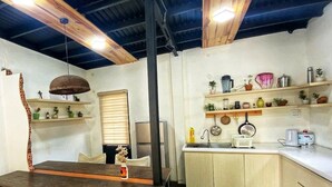 Een kleine keuken met houten kastjes, een eettafel en een hanglamp.