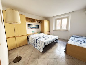 Una camera da letto con un letto, un comodino, una lampada, una finestra e un armadio.
