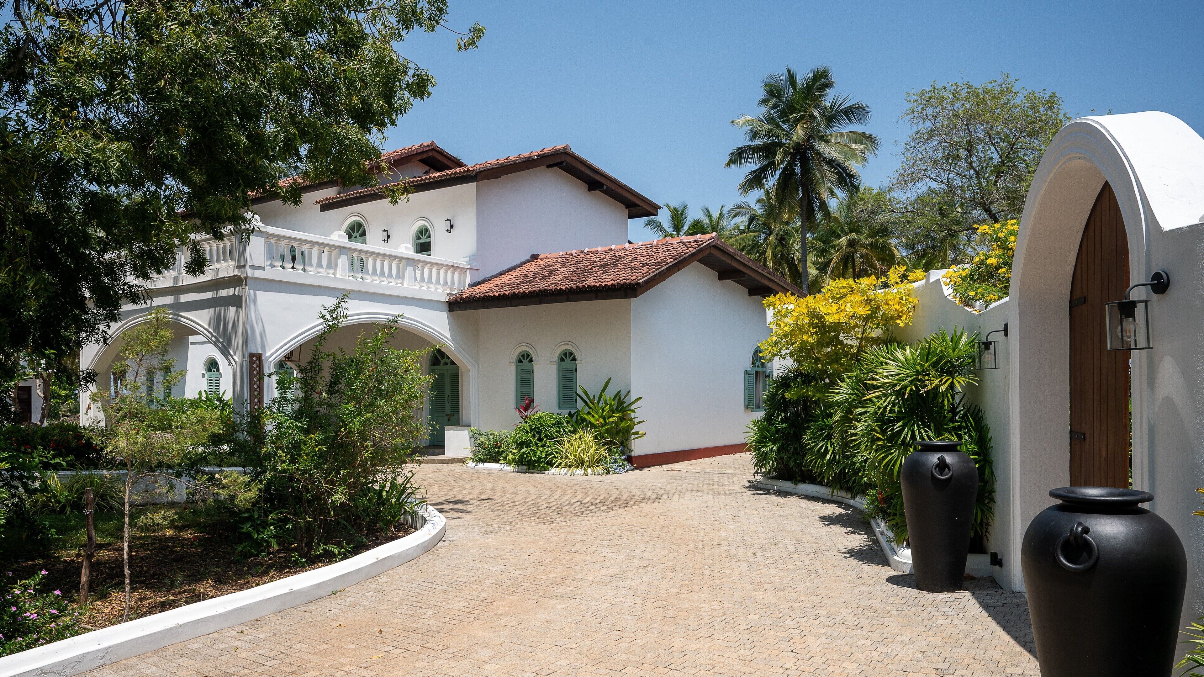 A white building with a red-tiled roof, arched windows, and a white balcony.