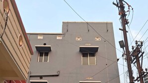 Un immeuble de deux étages, avec une enseigne indiquant « Hôtel Satya Inn » au rez-de-chaussée.