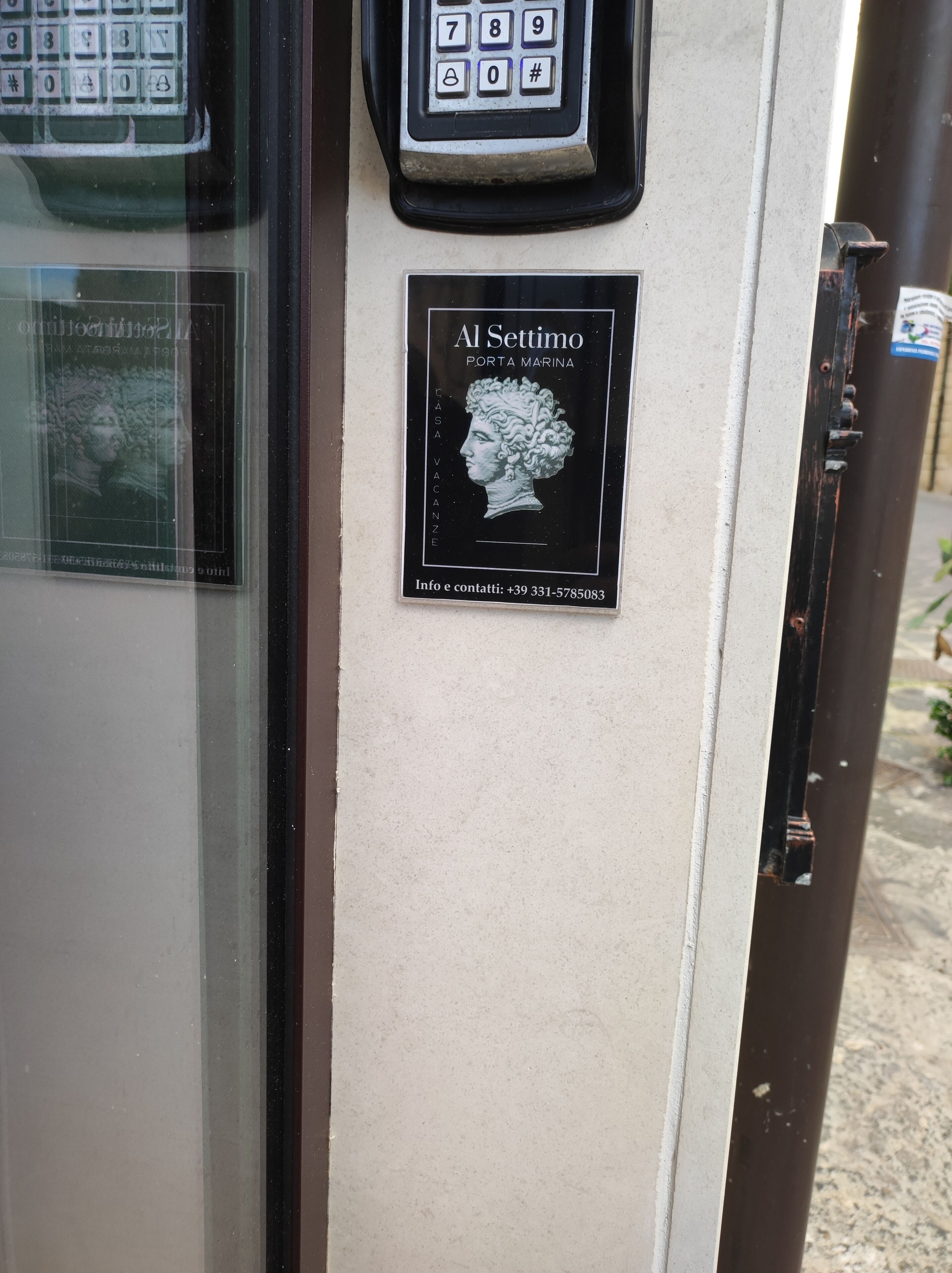 A keypad, a plaque with a bust, and a door handle.