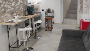 Eine moderne Küche mit Barbereich, einem Esstisch mit Stühlen, einer Couch und einer Treppe, die zu einer weiteren Ebene führt.