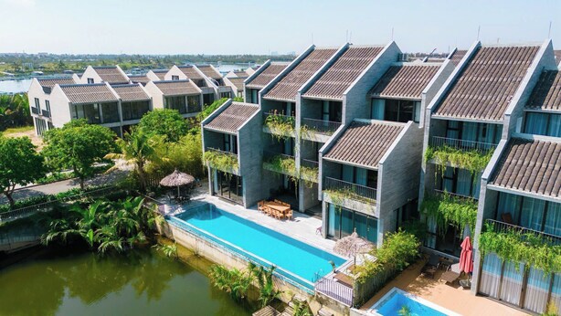 A modern hotel with multiple buildings, a swimming pool, and lush greenery. - Gold Riverside Apartment & Villa (Da Nang)