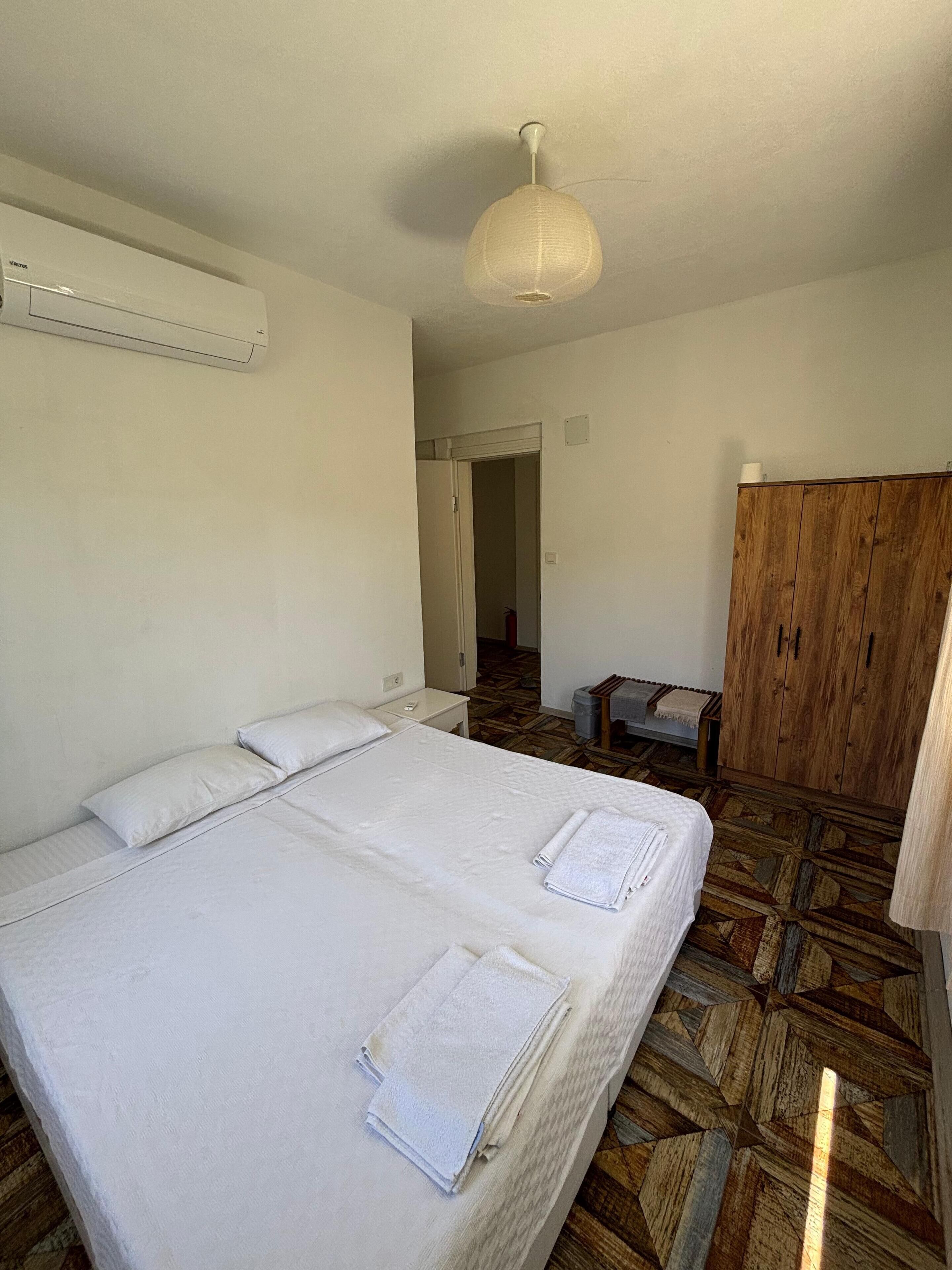 Habitación de hotel con una cama grande, un armario de madera y un ventilador de techo.