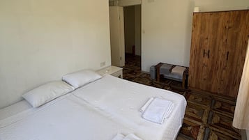 Habitación de hotel con una cama grande, un armario de madera y un ventilador de techo.