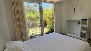 Ein Schlafzimmer mit einem großen Bett, einem Kleiderschrank und Blick auf Grün.