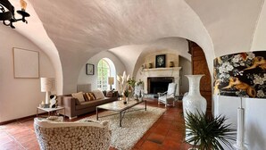 Amplia sala de estar con chimenea, un sofá, una mesa de centro y un sillón decorativo.