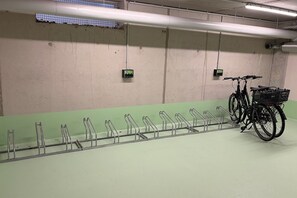 A parking garage with a row of bike racks and a bicycle with a basket.