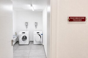 Ein sauberer, moderner Waschraum mit zwei Waschmaschinen und einem Schild, das ihn als Waschmaschinenraum kennzeichnet.