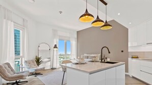 A modern kitchen with a central island, pendant lighting, and a view to the outside. - Spacious refurbished Studio steps away from metro (Dubai)