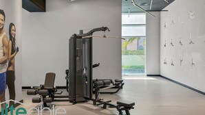 A modern gym with exercise equipment, a bench, and a wall with silhouettes of people exercising. - Spacious refurbished Studio steps away from metro (Dubai)
