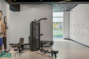 A modern gym with exercise equipment, a bench, and a wall with silhouettes of people exercising.