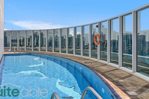 A swimming pool with glass walls, a lifebuoy, and a tiled floor.