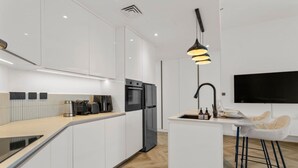 A modern kitchen with a built-in oven, a coffee maker, and a sink with a bar stool.