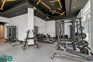 A modern gym with various weightlifting equipment, including dumbbells, a squat rack, and a bench press.
