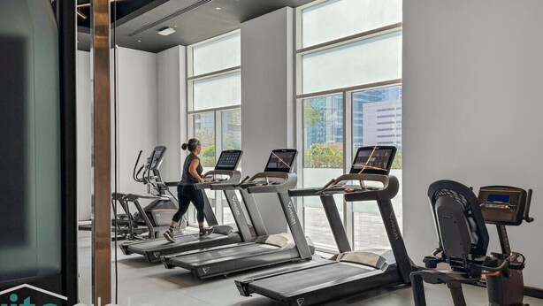 A gym with treadmills and a woman using one.