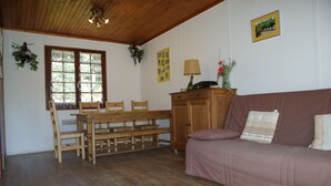 A cozy room with a wooden dining table, chairs, a sofa, and a cabinet. - House with swimming pool in exceptional surroundings (Ferrières-Poussarou)