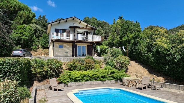 A two-story house with a balcony, surrounded by lush greenery and a swimming pool. - House with swimming pool in exceptional surroundings (Ferrières-Poussarou)